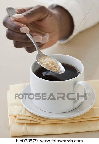 Stock Photo - African woman putting sugar in coffee. Fotosearch