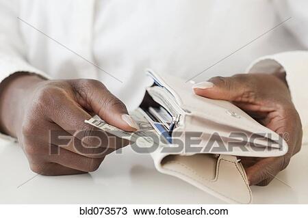 Stock Image - African woman taking money out of wallet. Fotosearch