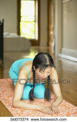 Picture - Asian woman kneeling on exercise mat. Fotosearch