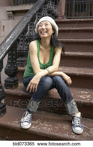 Stock Photography - Asian woman sitting on front steps. Fotosearch