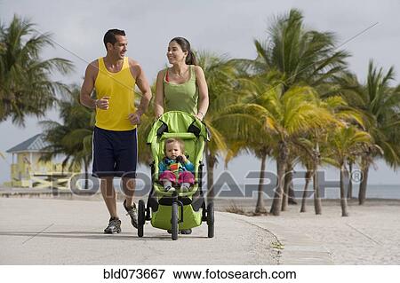 Stock Photo - Hispanic couple pushing baby in jogging stroller. Fotosearch