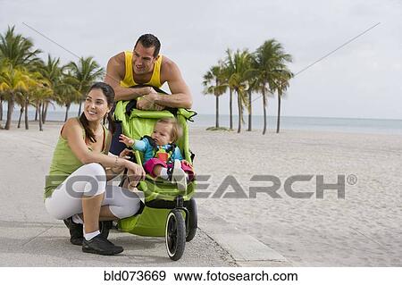 Stock Photo - Hispanic couple stopping with baby in jogging stroller. Fotosearch