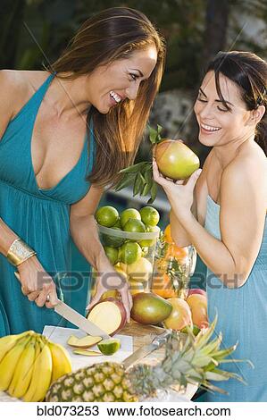 Stock Image - Hispanic friends preparing fresh fruit. Fotosearch