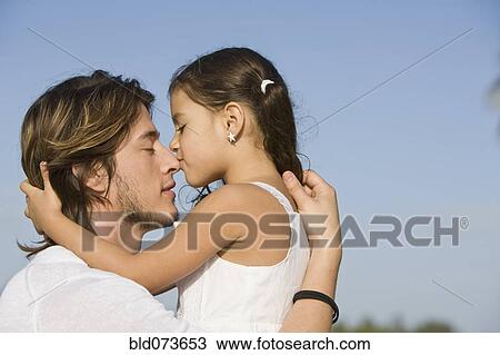 Stock Image - Hispanic girl kissing father. Fotosearch