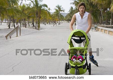 Stock Photography - Hispanic man on roller blades pushing jogging stroller. Fotosearch