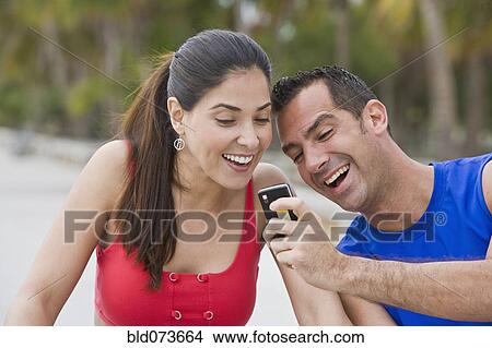 Hispanic man showing girlfriend cell phone View Large Photo Image Picture - Hispanic man showing girlfriend cell phone. Fotosearch