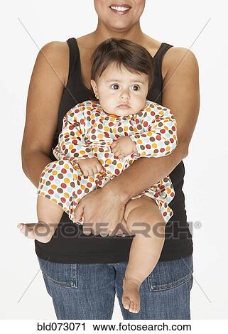 Stock Image - Hispanic mother holding baby daughter. Fotosearch