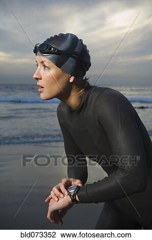 Stock Image - Hispanic woman in wetsuit on beach. Fotosearch