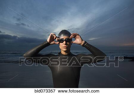 Stock Photo - Hispanic woman in wetsuit on beach. Fotosearch