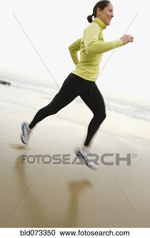 Stock Image - Hispanic woman running on beach. Fotosearch