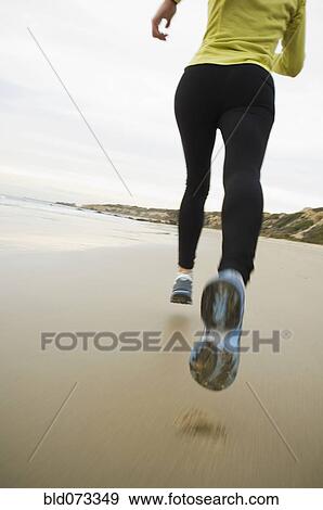Stock Photo - Hispanic woman running on beach. Fotosearch
