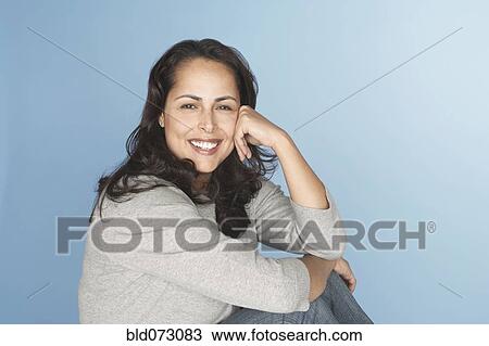 Stock Image - Hispanic woman smiling with head in hands. Fotosearch