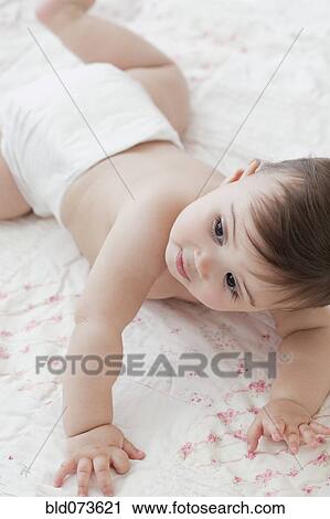 Stock Image - Mixed race baby girl crawling on blanket. Fotosearch