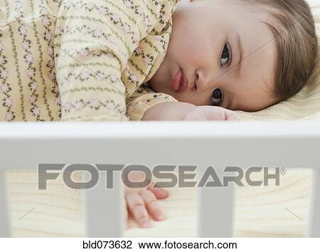 Stock Image - Mixed race baby girl laying in crib. Fotosearch