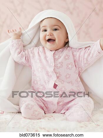 Stock Photography - Mixed race baby girl playing peek-a-boo under blanket. Fotosearch