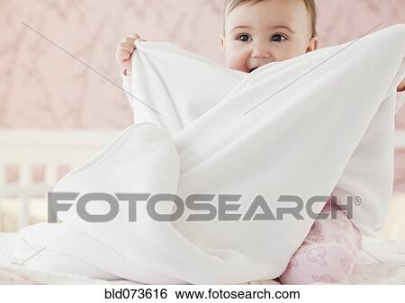 Stock Photograph - Mixed race baby girl playing with blanket. Fotosearch