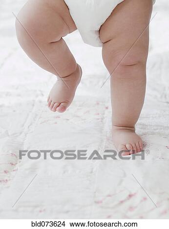 Picture - Mixed race baby girl walking on blanket. Fotosearch