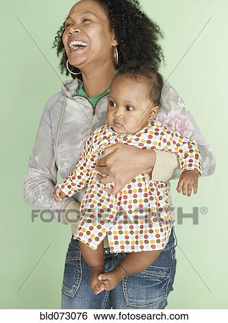 Stock Photograph - Mixed race mother holding baby daughter. Fotosearch