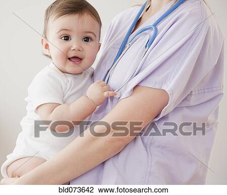 Stock Image - Nurse holding mixed race baby girl. Fotosearch