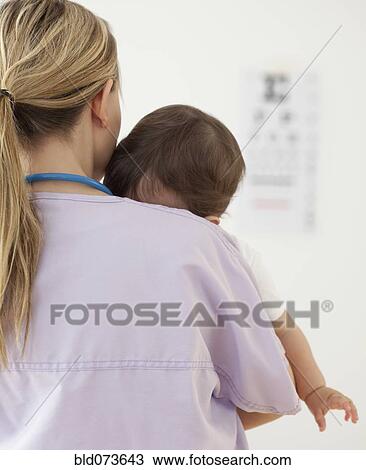 Stock Image - Nurse holding mixed race baby girl. Fotosearch