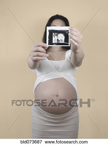 Pregnant Chinese woman holding out sonogram image View Large Photo Image Stock Photo - Pregnant Chinese woman holding out sonogram image. Fotosearch