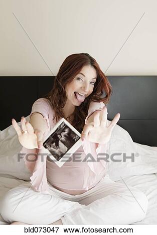 Pregnant Hispanic woman holding sonogram picture View Large Photo Image Stock Photo - Pregnant Hispanic woman holding sonogram picture. Fotosearch