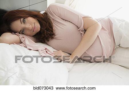 Stock Image - Pregnant Hispanic woman laying in bed. Fotosearch