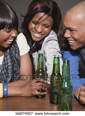 Stock Photo - African friends drinking beer in nightclub. Fotosearch