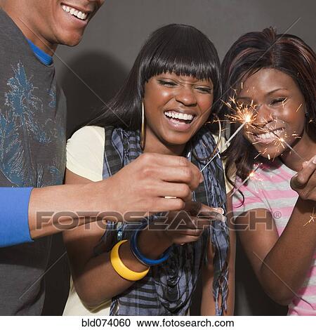 Stock Image - African friends enjoying sparklers. Fotosearch
