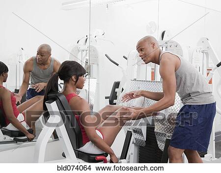 African man helping woman on exercise equipment View Large Photo Image Picture - African man helping woman on exercise equipment. Fotosearch