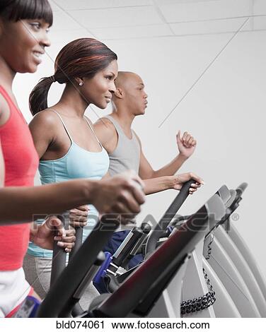 Stock Image - African people using exercise equipment in health club. Fotosearch