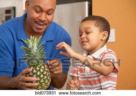 Stock Image - Antiguan father showing pineapple to son. Fotosearch