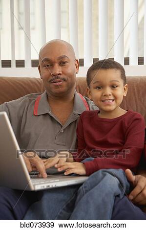 Stock Photo - Antiguan father using laptop with son. Fotosearch
