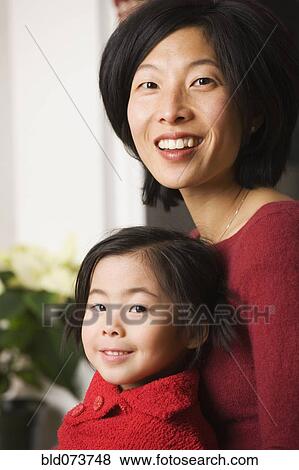 Asian mother with daughter in lap View Large Photo Image Stock Photo - Asian mother with daughter in lap. Fotosearch