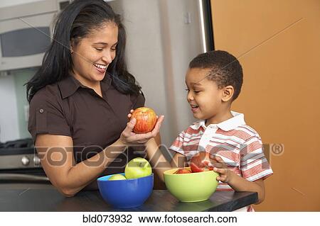 Dominican mother handing son an apple View Large Photo Image Stock Image - Dominican mother handing son an apple. Fotosearch