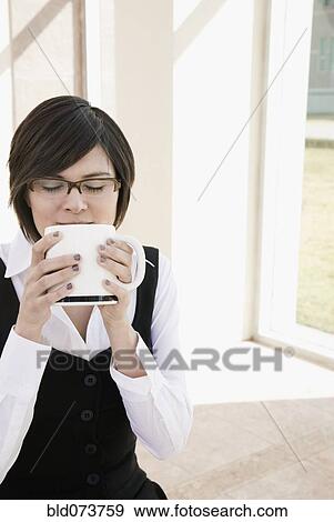 Stock Photo - Hispanic businesswoman drinking coffee outdoors. Fotosearch