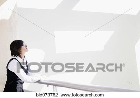 Stock Image - Hispanic businesswoman standing in office lobby. Fotosearch