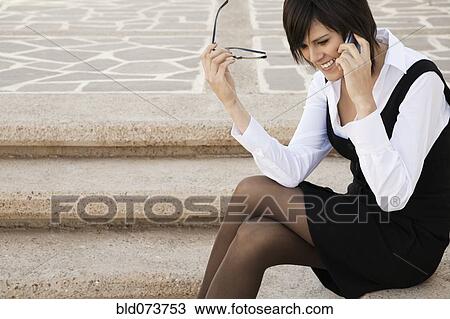 Stock Image - Hispanic businesswoman talking on cell phone outdoors. Fotosearch