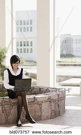 Stock Photo - Hispanic businesswoman using laptop outdoors. Fotosearch