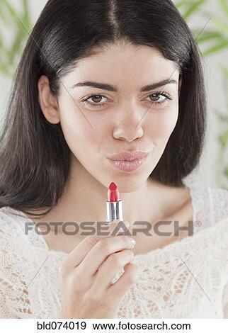 Stock Photo - Hispanic woman applying lipstick. Fotosearch