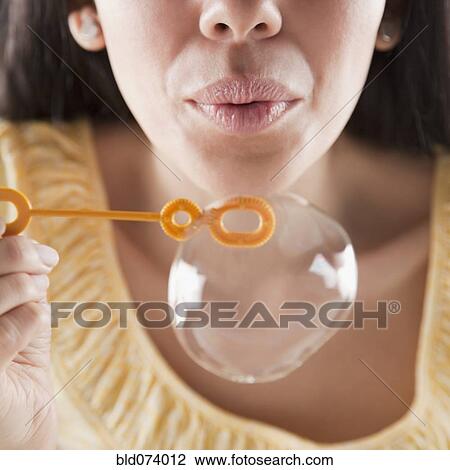 Stock Image - Hispanic woman blowing bubbles. Fotosearch