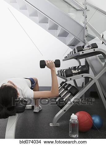Picture - Hispanic woman using hand weights in health club. Fotosearch