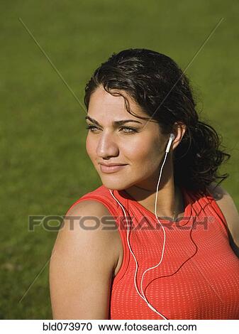 Stock Image - Middle Eastern woman listening to music in park. Fotosearch