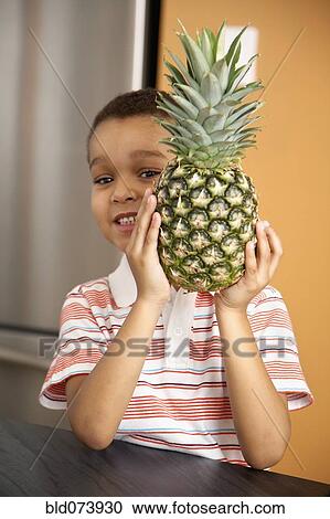 Mixed race boy holding pineapple View Large Photo Image Stock Image - Mixed race boy holding pineapple. Fotosearch