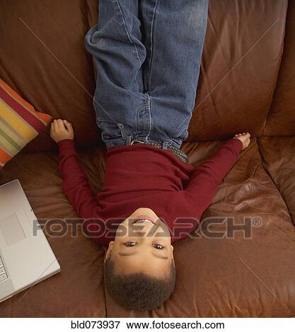 Mixed race boy laying upside down on couch View Large Photo Image Stock Photo - Mixed race boy laying upside down on couch. Fotosearch