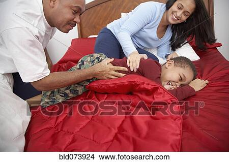 Parents tickling mixed race boy on bed View Large Photo Image Picture - Parents tickling mixed race boy on bed. Fotosearch
