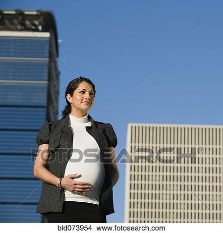 Picture - Pregnant Middle Eastern woman rubbing stomach. Fotosearch