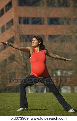 Stock Photo - Pregnant Middle Eastern woman practicing yoga in park. Fotosearch
