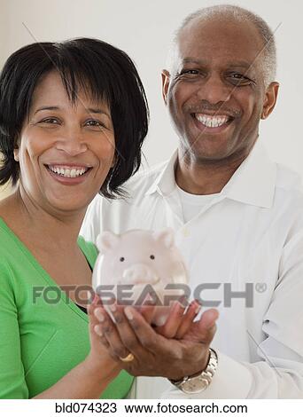 Stock Image - African couple holding piggy bank. Fotosearch