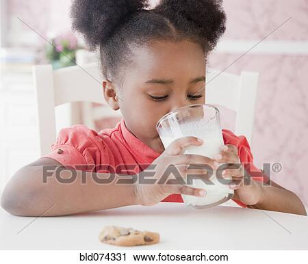 Stock Image - African girl drinking milk with cookie. Fotosearch
